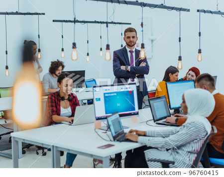 Group of multi-ethnic colleagues working on desktop computers, laptop and sharing their ideas in a modern office space.Young influencers work on online marketing projects. Group of multi-ethnic colleagues working on desktop computers, laptop and sharing their ideas in a modern office space.Young influencers work on online marketing projects. 96760415