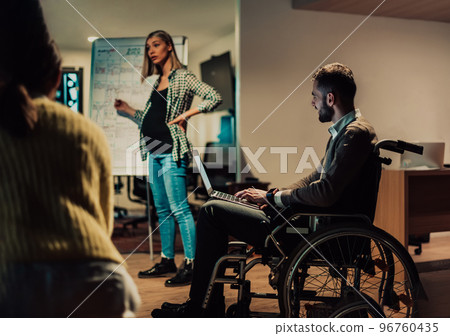 A pregnant businesswoman leads a creative meeting of a diverse business team in a modern coworking A pregnant businesswoman leads a creative meeting of a diverse business team in a modern coworking 96760435