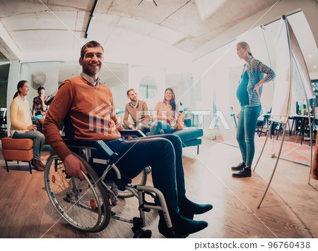 A pregnant businesswoman leads a creative meeting of a diverse business team in a modern coworking 96760438