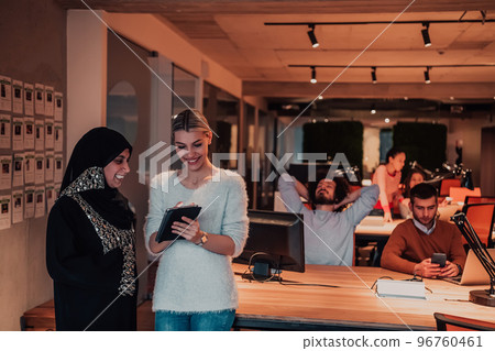 Muslim businesswoman woman and young businesswoman in a modern office solve a problem together while using a tablet 96760461