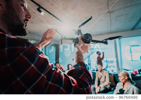 A bearded man in a modern office explaining to his young diverse team how a drone working  96760480