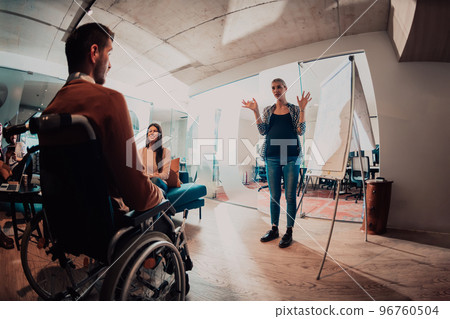 A pregnant businesswoman leads a creative meeting of a diverse business team in a modern coworking 96760504
