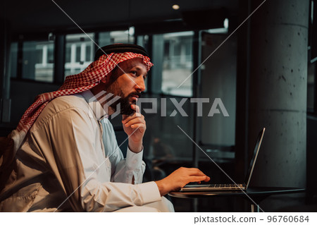 An elderly Arab man sitting in the office and analyzes data on his laptop An elderly Arab man sitting in the office and analyzes data on his laptop 96760684