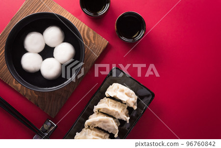 Tang Yuan(sweet dumplings balls), a traditional cuisine for Mid-autumn, Dongzhi (winter solstice ) and Chinese new year with plum flower and tea on red background. Tang Yuan(sweet dumplings balls), a traditional cuisine for Mid-autumn, Dongzhi (winter solstice ) and Chinese new year with plum flower and tea on red background. 96760842
