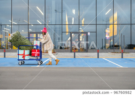 Woman buys Christmas tree and presents at mall Woman buys Christmas tree and presents at mall 96760982