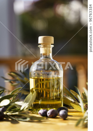 Olive oil with olive tree branch background. Natural oil for food or cosmetics from natural ingredients. Healthy food, cosmetics concept. 96763384