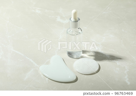 Face care concept with gua sha and cosmetic on light textured background Face care concept with gua sha and cosmetic on light textured background 96763469
