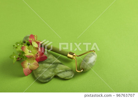 Lifting and toning treatment concept with gua sha on green background Lifting and toning treatment concept with gua sha on green background 96763707