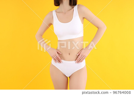 Concept of weight loss with slim young woman on yellow background 96764008