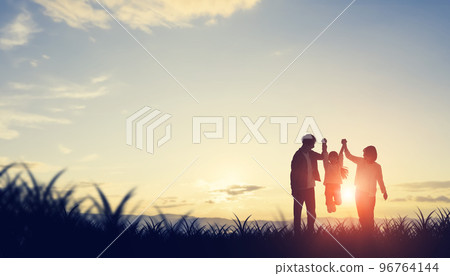 Silhouette of parent and child walking in the meadow with the sun in the background 96764144