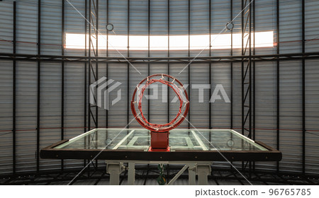 View from bottom of Basketball fiberglass backboard, Hoop red metal ring and white net against Ceiling sheet metal in the gym. View from bottom of Basketball fiberglass backboard, Hoop red metal ring and white net against Ceiling sheet metal in the gym. 96765785