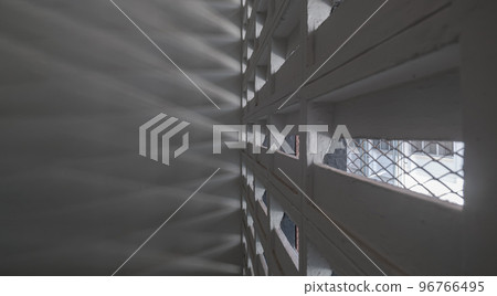 The sunlight shines through light channels wall of old gymnasium. Concrete walls have holes for sunlight to penetrate through the holes from the outside. 96766495