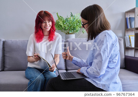 Teenage girl student talking with female teacher, sitting together in office Teenage girl student talking with female teacher, sitting together in office 96767364