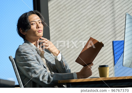 Young businessman working by the window in the office Young businessman working by the window in the office 96767370