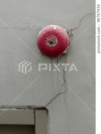 Old and dirty Red fire alarm bell on white concrete wall on top of Emergency fire exit door. Old and dirty Red fire alarm bell on white concrete wall on top of Emergency fire exit door. 96767439