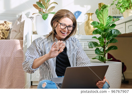 Mature woman using laptop for conference video call, sitting at home Mature woman using laptop for conference video call, sitting at home 96767907