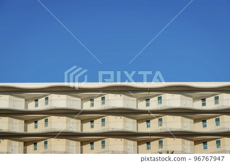 View of a building from below with painted beige walls and white doors at balconies in Destin, FL View of a building from below with painted beige walls and white doors at balconies in Destin, FL 96767947