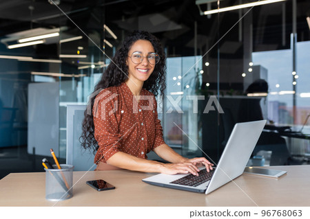Young beautiful hispanic woman working inside modern office, businesswoman smiling and looking at camera at work using laptop. 96768063