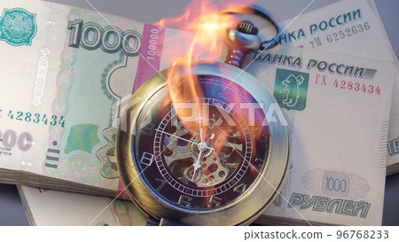 Burning pocket watch with pile of money in wrapper 96768233