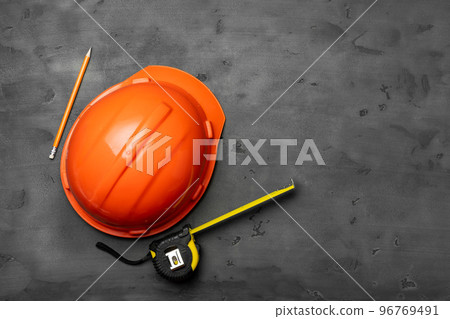 Orange hardhat, ruler and pencil on black background Orange hardhat, ruler and pencil on black background 96769491