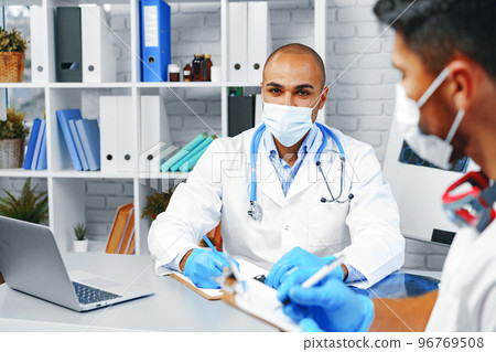 Two male doctors discussing their work in cabinet Two male doctors discussing their work in cabinet 96769508