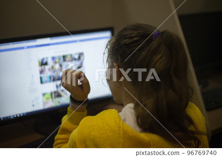 Girl looks at monitor. Girl searches on Internet. Student studies at computer. School class. 96769740