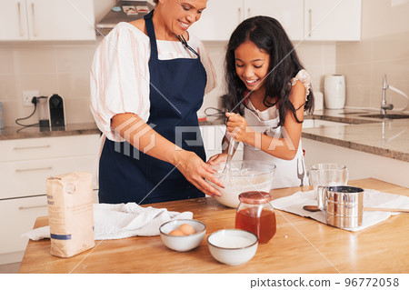 Granddaughter mixing dough in a bowl. Granny and girl baking together.	 96772058