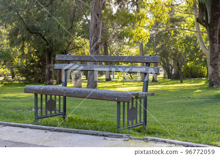 An empty bench in a green park by walking path An empty bench in a green park by walking path 96772059