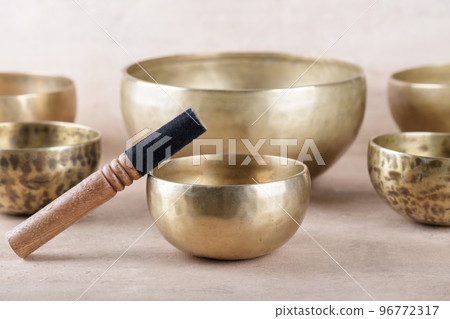 Tibetan singing bowls with sticks used during mantra meditations on beige stone background, close up 96772317
