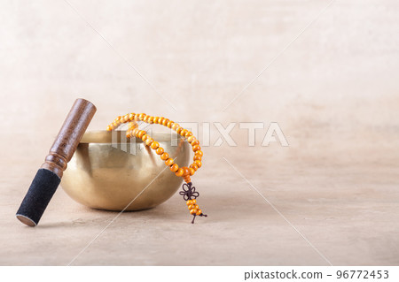 Tibetan singing bowl with stick, mala beads strands used during mantra meditations on beige stone background 96772453