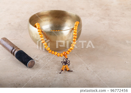 Tibetan singing bowl with stick, mala beads strands used during mantra meditations on beige stone background 96772456