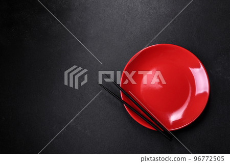 Empty plate with wooden sticks for Asian food on a dark concrete background Empty plate with wooden sticks for Asian food on a dark concrete background 96772505