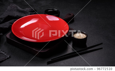 Empty plate with wooden sticks for Asian food on a dark concrete background Empty plate with wooden sticks for Asian food on a dark concrete background 96772510