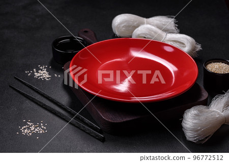 Empty plate with wooden sticks for Asian food on a dark concrete background Empty plate with wooden sticks for Asian food on a dark concrete background 96772512