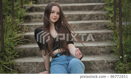 Nice girl posing while sitting on the stairs. Nice girl posing while sitting on the stairs. 96772851