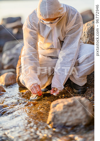 Close-up of researcher collecting water sample at seashore 96772946