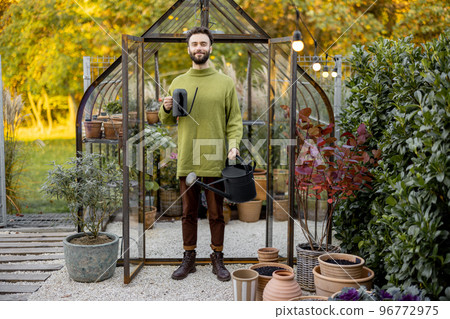 Stylish guy with watering can in garden 96772975