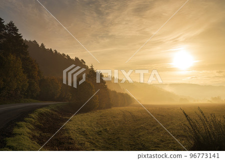 A bend of the road at the morning light of a foggy autumn land. 96773141