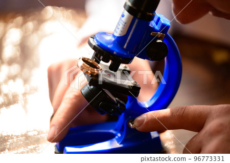 Microscope and human hands, a laboratory technician conducts research using a microscope. Microscope and human hands, a laboratory technician conducts research using a microscope. 96773331