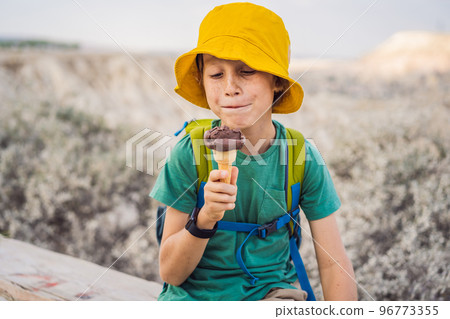 Boy tourist boy eating turkish ice cream while exploring valley with rock formations and fairy caves near Goreme in Cappadocia Turkey Boy tourist boy eating turkish ice cream while exploring valley with rock formations and fairy caves near Goreme in Cappadocia Turkey 96773355