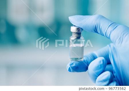 Doctor's hand holding glass vial with injection over blue background. Vaccination or beauty therapy concept. 96773562