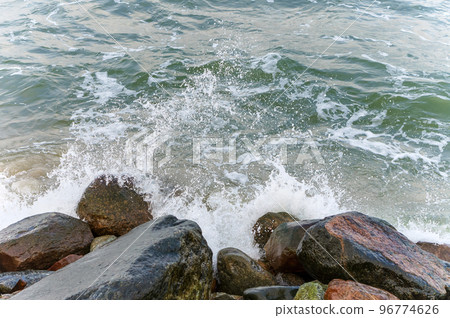 The waves of the sea crash on the rocks. Big rocks on the shore. Stony seashore. 96774626
