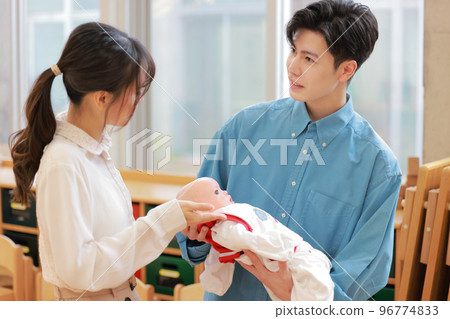 A man learning how to hold a baby and an instructor teaching him_2 A man learning how to hold a baby and an instructor teaching him_2 96774833