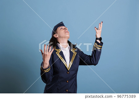 Flight attendant in uniform begging, praying to gods, looking upwards, raising hands to sky. Stewardess pleasing with hopeful facial expression, air hostess worshiping, praising Flight attendant in uniform begging, praying to gods, looking upwards, raising hands to sky. Stewardess pleasing with hopeful facial expression, air hostess worshiping, praising 96775389