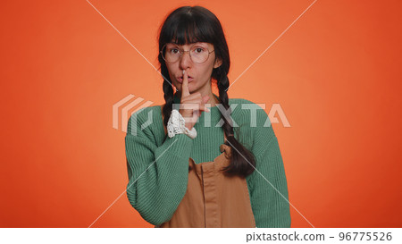 Young woman presses index finger to lips makes silence gesture sign do not tells secret shh be quiet Young woman presses index finger to lips makes silence gesture sign do not tells secret shh be quiet 96775526
