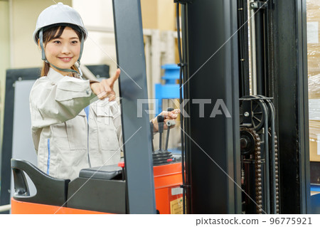 A female worker riding a forklift and confirming safety 96775921