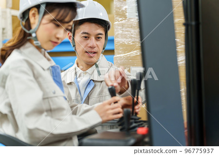 A worker giving advice on driving a forklift 96775937