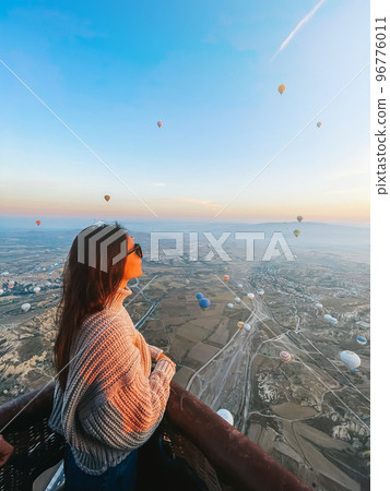 Happy woman during sunrise watching hot air balloons in Cappadocia, Turkey Happy woman during sunrise watching hot air balloons in Cappadocia, Turkey 96776011
