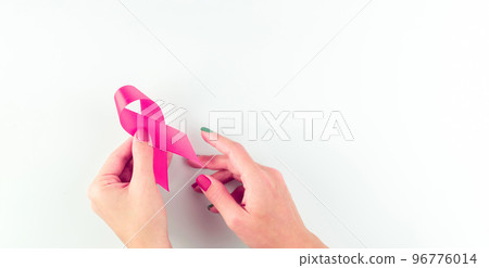 Cancer day. Health care symbol pink ribbon in woman hands on white background. Breast cancer support concept with copy space. Cancer day. Health care symbol pink ribbon in woman hands on white background. Breast cancer support concept with copy space. 96776014