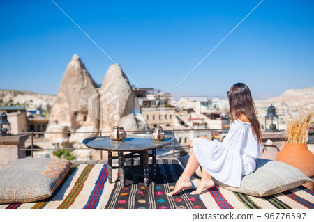 Happy young woman during vacation watching hot air balloons in Cappadocia, Turkey Happy young woman during vacation watching hot air balloons in Cappadocia, Turkey 96776397